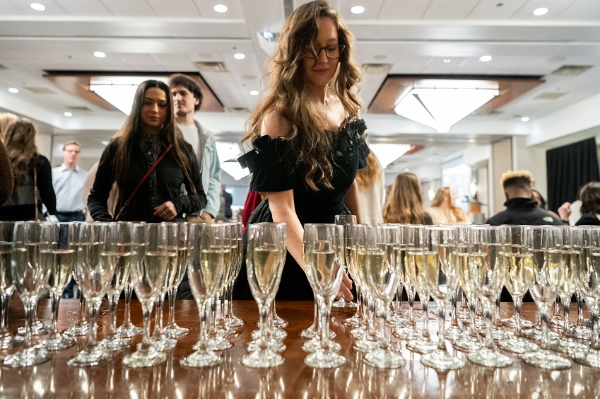 Graduate grabbing champagne glass at Senior Toast